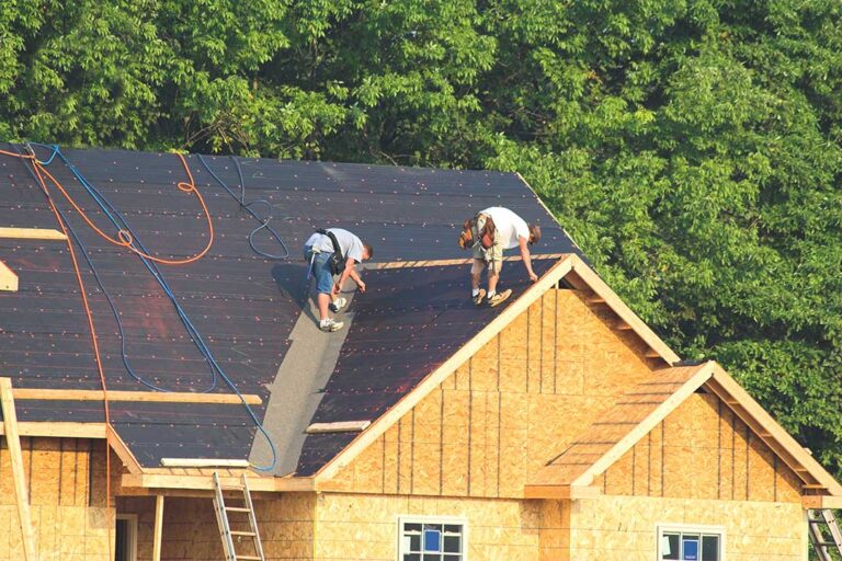 Homeowner viewing curled shingles and roof wear from the ground beside a suburban house.